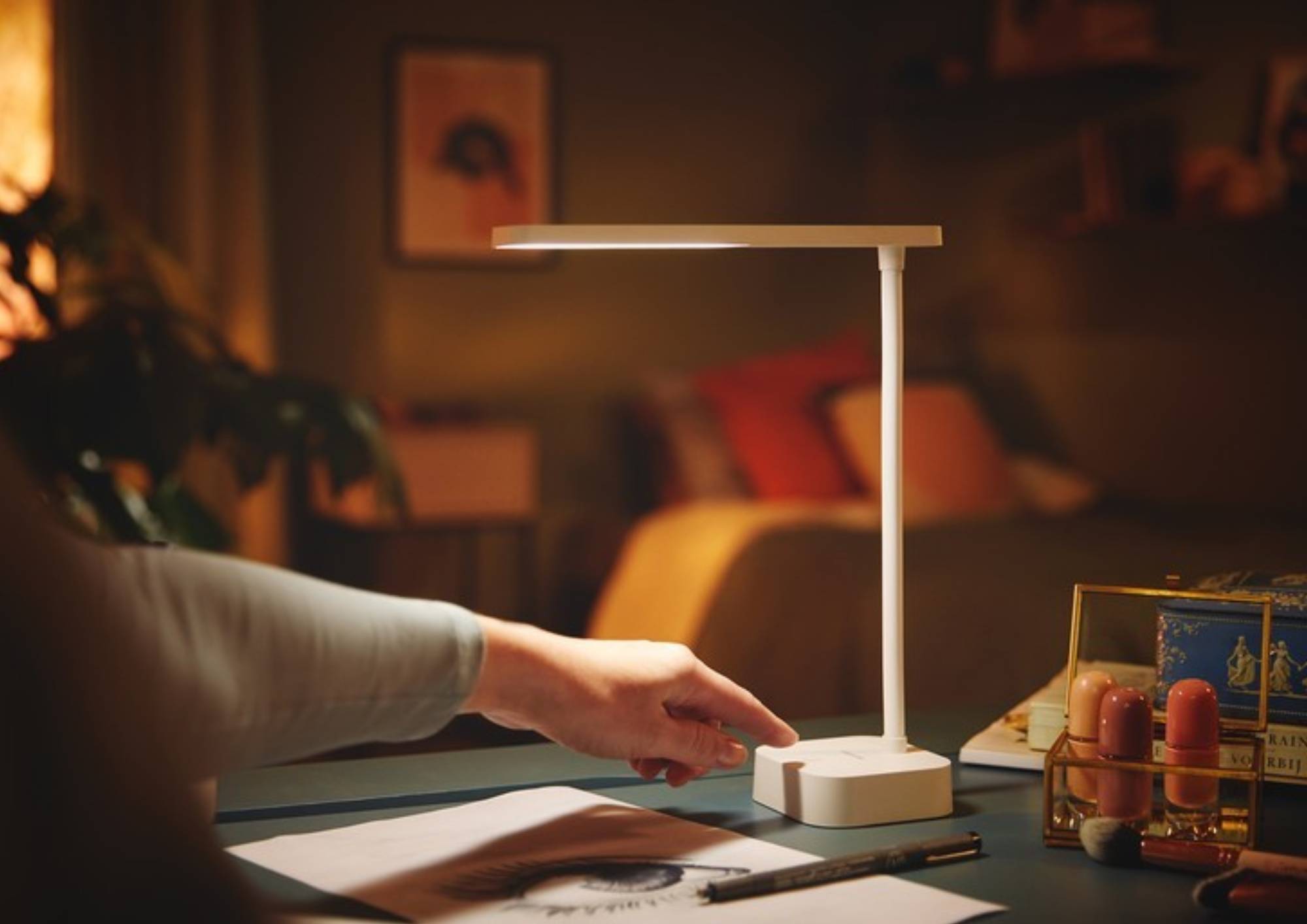 Ręka włączająca lampkę biurkową stojącą na biurku