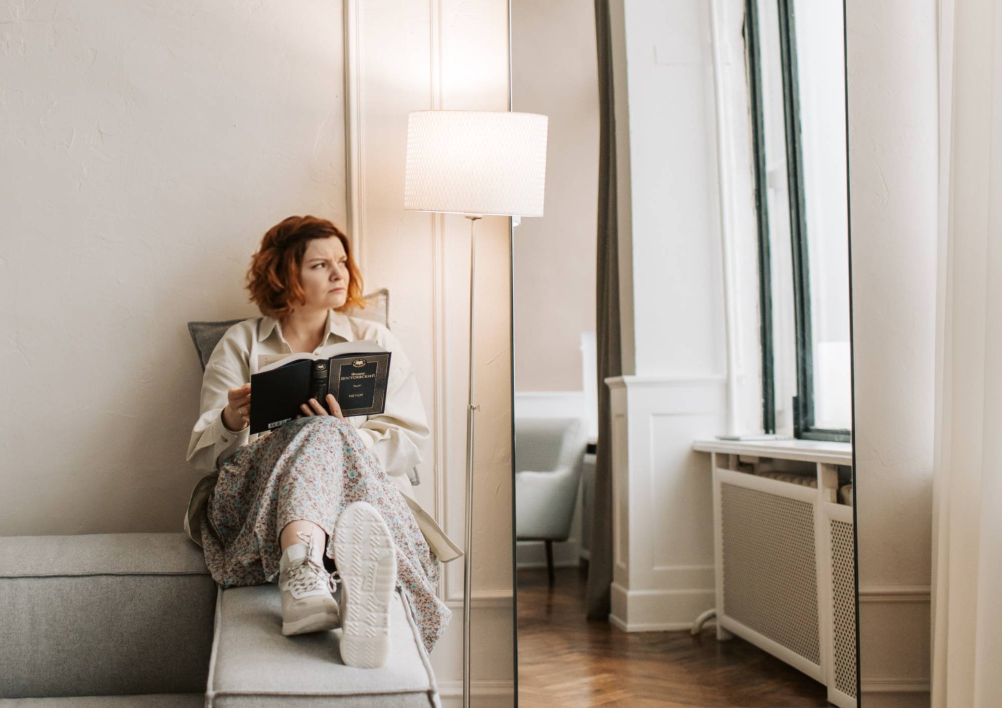 Kobieta siedząca na sofie przy włączonej lampie podłogowej w salonie